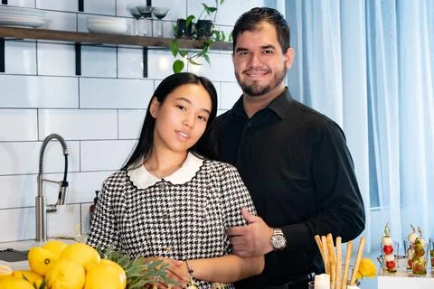 A couple of people stand at a set table with snacks, dishes and decorations Stock Photos