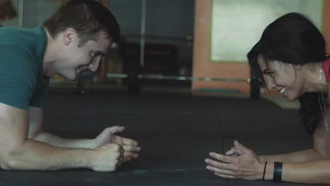 Couple performs challenging plank exercise in gym while touching hands Stock Footage 312724806