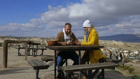 Couple with phones relaxing on the top overlooking the rocky valley 스톡 동영상 101111453