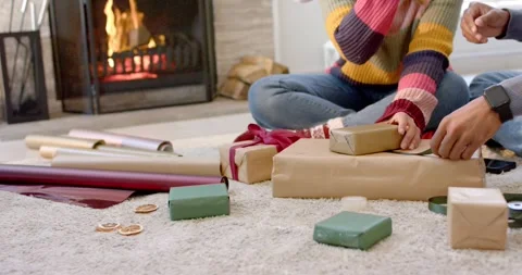 Couple picking up dried orange slice and tying green ribbon while wrapping gift Stock Footage 339557801