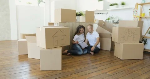 Couple planning their new kitchen siting on the floor. young family moving to a Stock Footage 76145045