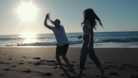 Couple playing and running barefoot on the beach at sunset enjoying the moment Stock-Footage 323501650