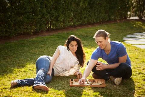 Couple playing Backgammon game at grassy field Stock Photos