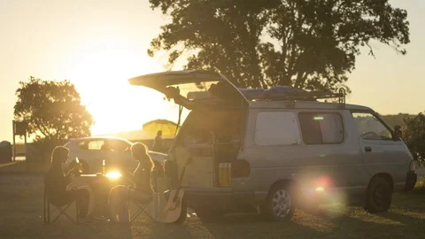 Couple playing cards next to campervan camping with sunset Stock Footage