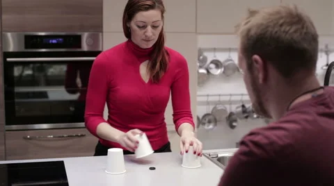 Couple playing a game with three glasses and ball Stock Footage 59191354