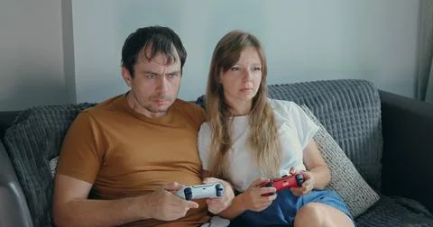 Couple playing games on couch with controllers Stock Photos