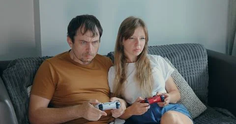 Couple playing games on couch with intense expressions Stock Photos