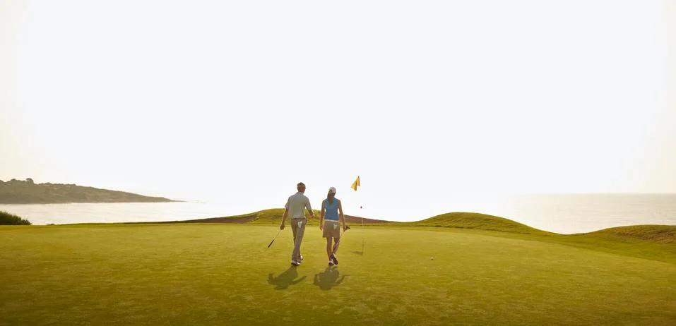 Couple playing golf on course Fotos Stock