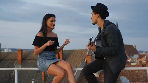 Couple playing guitar on a rooftop Stock Footage 99965727