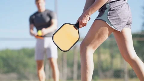 Couple playing pickleball game, hitting pickleball yellow ball with paddle Stock-Footage 229318332