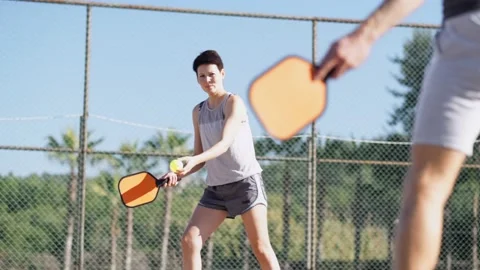 Couple playing pickleball game, hitting pickleball yellow ball with paddle Stock-Footage 229318384