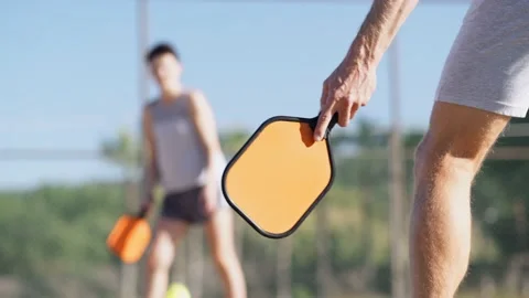 Couple playing pickleball game, hitting pickleball yellow ball with paddle Stock-Footage 229472644