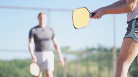 Couple playing pickleball game, hitting pickleball yellow ball with paddle Stock-Footage 229472664