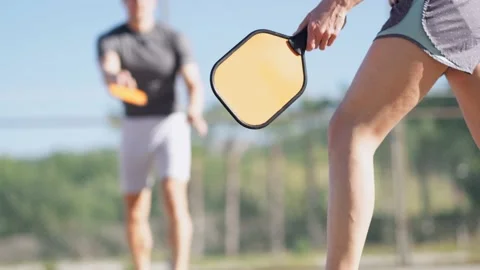 Couple playing pickleball game, hitting pickleball yellow ball with paddle Stock-Footage 230044738