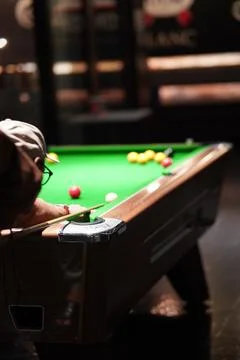 Couple playing pool. Aiming at pool balls with pool cues. Stock Photos