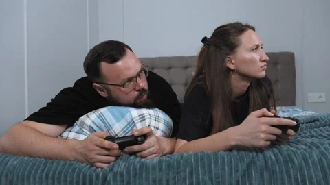 Couple playing videogames on bed Stock Footage 317442137