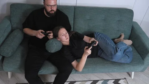 Couple playing videogames on sofa at home 库存影片 317441997