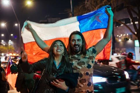 A couple pose for the camera while holding up the Chilean Flag at a public event Stock Photos