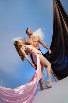 Couple posing dramatically in studio with flowing fabric and angelic elements Fotos Stock