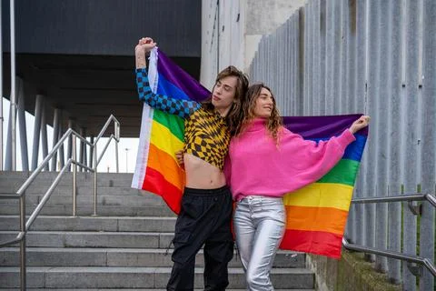 Couple posing with pride flag in front of stairs dressed in brightly colore.. Stock Photos