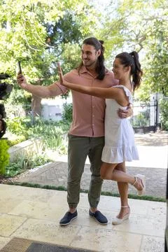 Couple posing for selfie on stone-paved patio, man holding smartphone, woman in Stock Photos