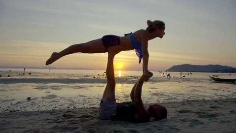 Couple practicing Acro Yoga on beach during sunset Stock Footage 74775132