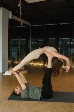 Couple practicing acro yoga in a spacious studio with soft lighting during .. Stock Photos