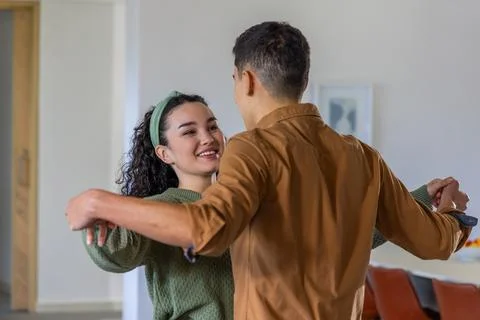 Couple practicing dance steps in residential living dining area, woman wearing Stock Photos