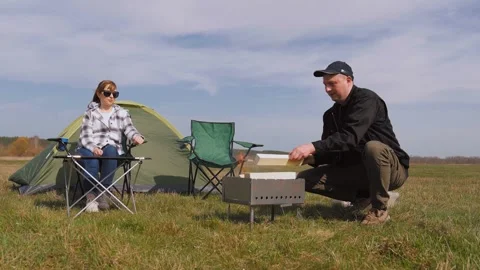 Couple preparing a barbecue grill during a camping trip in nature Stock Footage 319791166