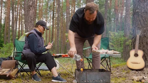 Couple preparing a barbecue on a grill during a forest camping trip Stock Footage 327136526