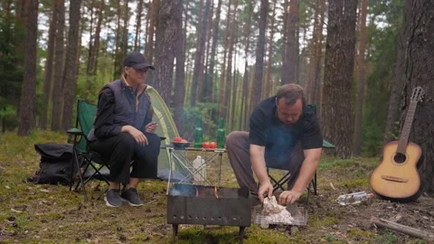 Couple preparing barbecue on a grill in the forest 库存影片 327130895