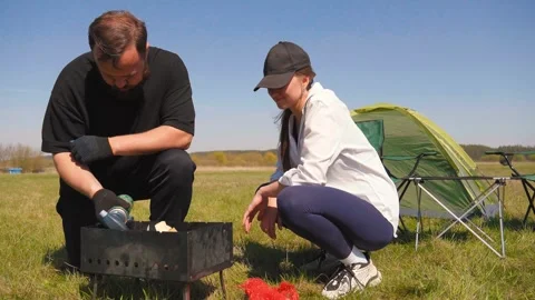 Couple preparing a barbecue while camping in nature Видео 344602971