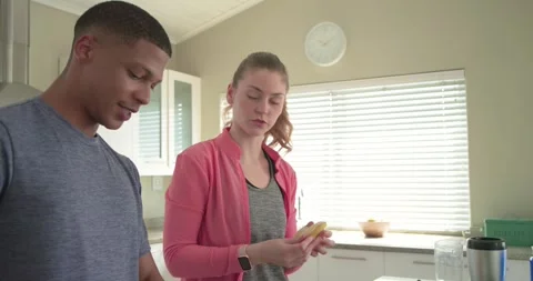 Couple preparing blender ingredients, man slicing cucumber on board while woman Stock Footage 344534974