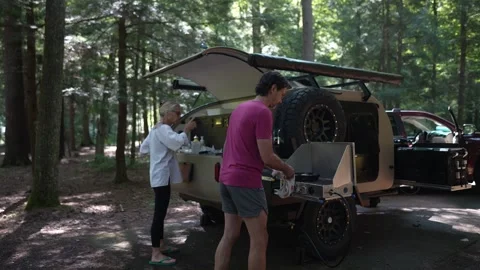 Couple Preparing Breakfast in a Teardrop Trailer at a Forest Campground Stock Footage 313883101