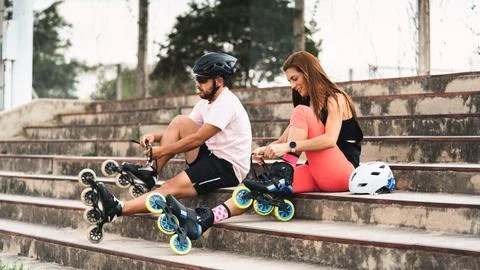 Couple preparing inline skates tying laces on steps Stock Photos