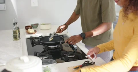 Couple preparing meal at counter man turning burner knob melting butter in pan Stockbeeldmateriaal 337289322