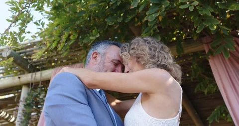 Couple pressing foreheads, holding each other under pergola, sharing affection Stock Footage 339559792