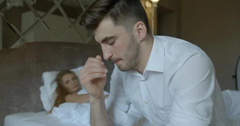 Couple with problems in bed. The depressed brunet is worrying while sitting on Stock Footage 86385247