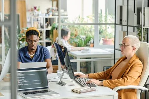 Couple of programmers working on computers at table Stock-Fotos