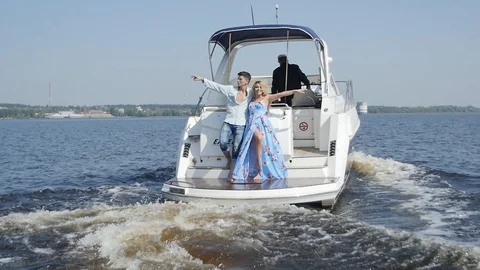 Couple put Their Hands to the Sides Standing on the Back of the Boat Stock Footage 87972559