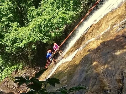 Couple rappelling down the waterfall Stock Photos