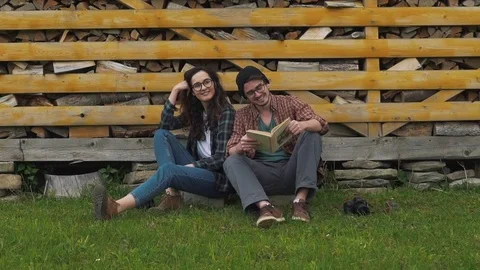 Couple reading book on the background of firewood Stock Footage 76246562