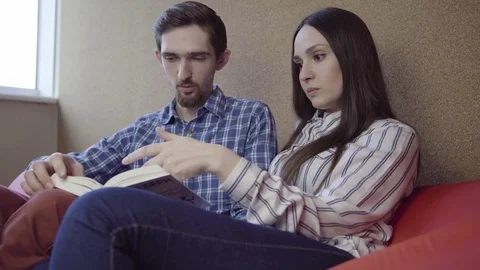 Couple reading book on the sofa Stock Footage 74716974