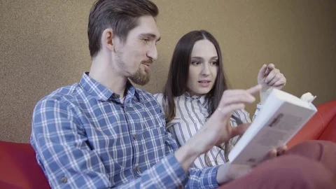 Couple reading book on the sofa Vídeo Stock 74717455