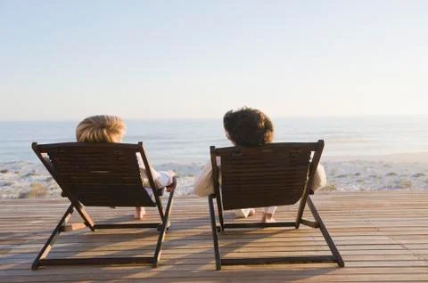 Couple reclining on deck chairs on the beach Stock Photos