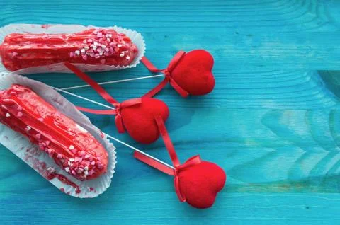Couple of red raspberry eclairs with red velvet hearts on blue wooden backgro Stock Photos