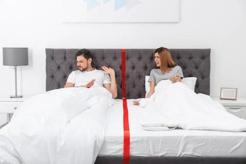 Couple with relationship problems arguing while lying separately in bed at ho Stock Photos