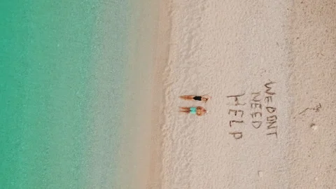 Couple relax on remote turquoise beach beside playful We dont need help sand Stock Footage 343241798