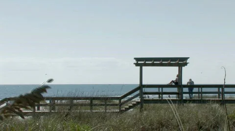 Couple relaxes on ocean boardwalk Stock Footage