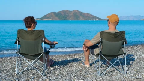 Couple relaxing on beach chairs, enjoying scenic ocean view Stock Footage 329054788